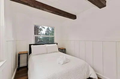 a bedroom with a bed with white sheets and a window at Highland Cedar Cabin WHot Tub Close to Village in Big Bear Lake