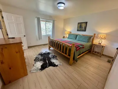 a bedroom with a bed and a table and a window at Lakewood Timber Lodge Peaceful Private in Big Bear Lake