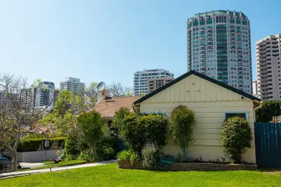 a small white house in a city with tall buildings at The Rochester house in Los Angeles