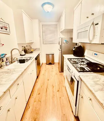 a kitchen with white cabinets and a wooden floor at Cozy private room in Santa Monica in Los Angeles