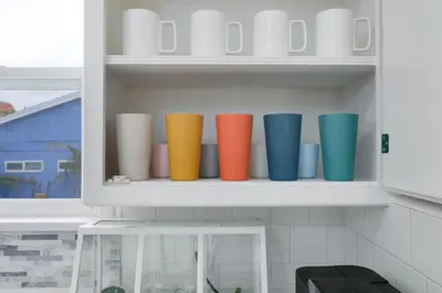 a row of colorful cups on a shelf in a kitchen at Mar Vista Beach Escape 2BR with Relaxing Yard in Los Angeles