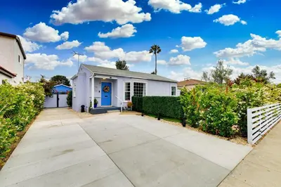 a white house with a blue door in a yard at Mar Vista Beach Escape 2BR with Relaxing Yard in Los Angeles