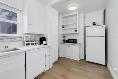 a white kitchen with white cabinets and a refrigerator at Mar Vista Beach Escape 2BR with Relaxing Yard in Los Angeles