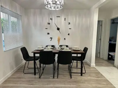 a dining room table with chairs and a clock on the wall at Walkable to SoFi, Intuit Dome, Kia Forum World Cup in Inglewood