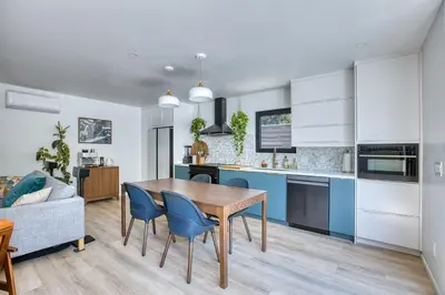a kitchen and dining room with a wooden table and blue chairs at Brand-New MCM Guesthouse in West Los Angeles in Los Angeles