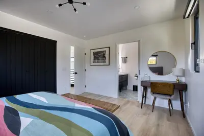 a bedroom with a bed and a desk and a mirror at Brand-New MCM Guesthouse in West Los Angeles in Los Angeles