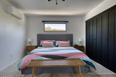 a bedroom with a bed with a bench in it at Brand-New MCM Guesthouse in West Los Angeles in Los Angeles