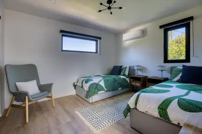 a bedroom with two beds and a chair and a window at Brand-New MCM Guesthouse in West Los Angeles in Los Angeles