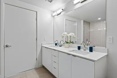 a white bathroom with two sinks and a large mirror at Nautical Knees Water View Pool, Jacuzzi and Gym in Los Angeles