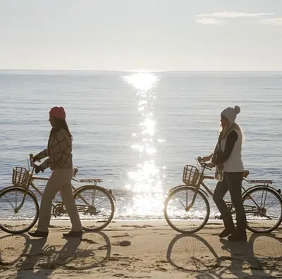 two women walking their bikes on the beach at Nautical Knees Water View Pool, Jacuzzi and Gym in Los Angeles