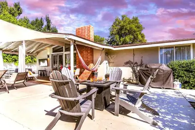 a patio with chairs and a table and a house at SoCal Retreat with Pool and Spacious Backyard in Canoga Park