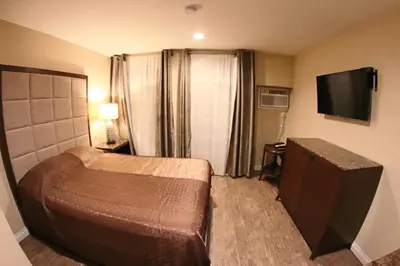 a hotel room with a bed and a flat screen tv at Santa Cruz Inn in Riverside