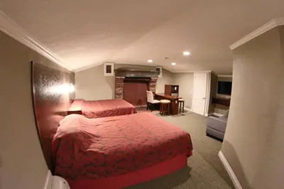 a hotel room with two beds and a fireplace at Santa Cruz Inn in Riverside