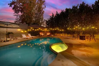 a swimming pool with lights in a backyard at night at Valley Oasis Pool Hot Tub Near Universal in Garnsey