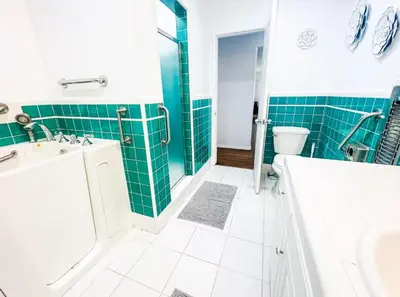 a bathroom with green tiles and a tub and a toilet at Valley Oasis Pool Hot Tub Near Universal in Garnsey