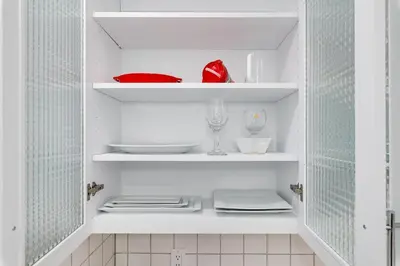 a white cupboard with plates and dishes on it at Valley Oasis Pool Hot Tub Near Universal in Garnsey