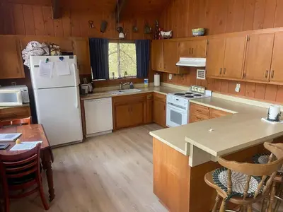 a kitchen with wooden cabinets and a white refrigerator at Pet Friendly 3BR Pine Mountain Club Cabin with King Bed and Pool Access in Pine Mountain Club