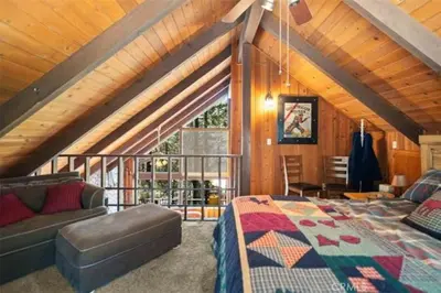 a attic bedroom with a bed and a couch at Pet Friendly 3BR Pine Mountain Club Cabin with King Bed and Pool Access in Pine Mountain Club