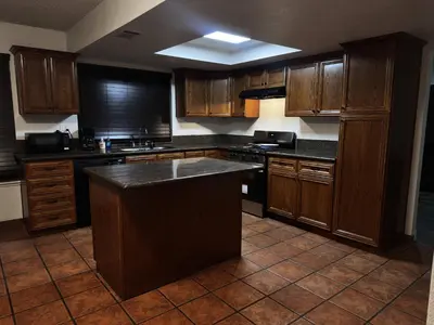 a kitchen with wooden cabinets and a large island in it at Brick & Breeze in Bakersfield