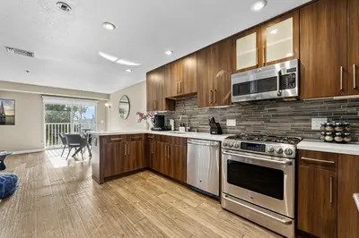 a kitchen with stainless steel appliances and wooden cabinets at Vertical Blue Bi-Level Sanctuary with Pacific Vistas in Los Angeles