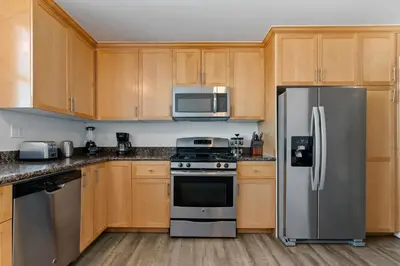 a kitchen with wooden cabinets and stainless steel appliances at The Glass Anchor - 2 Bed Front-Row Marina Suite in Los Angeles