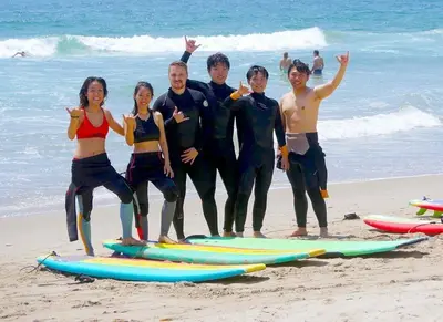 a group of people standing on the beach with surfboards at The Glass Anchor - 2 Bed Front-Row Marina Suite in Los Angeles