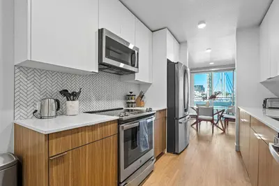 a kitchen with white cabinets and stainless steel appliances at Urban Tide - A Designer Escape Overlooking the Docks in Los Angeles