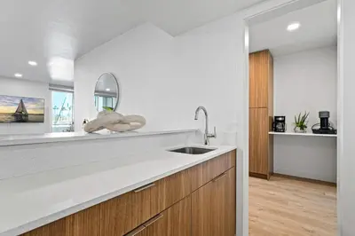 a white kitchen with a sink and a mirror at Urban Tide - A Designer Escape Overlooking the Docks in Los Angeles