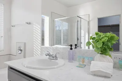 a white bathroom with a sink and a mirror at Serenity House in Bakersfield