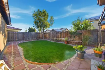 a small backyard with a fence and a green lawn at Serenity House in Bakersfield