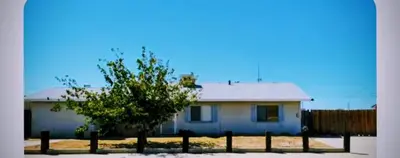 a white house with a tree in front of it at The Joshua House in Boron