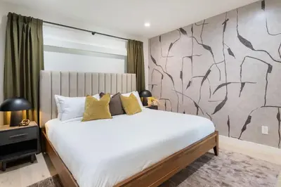 a bedroom with a large white bed and a wall at The Drift Manhattan Beach - steps to the ocean in Manhattan Beach