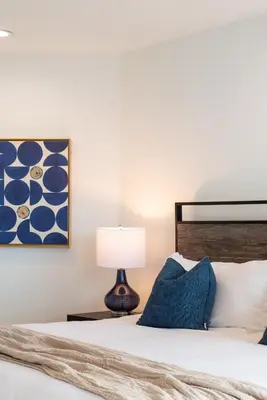 a bedroom with a bed with a lamp and a painting at The Zenith Penthouse - Ocean Panoramas & Salt Air in Los Angeles