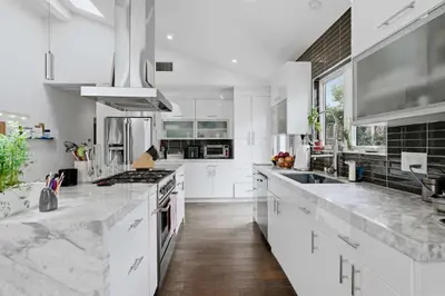 a white kitchen with marble counter tops and appliances at New Listing West LA Urban Oasis by Colby & Conrad in Los Angeles