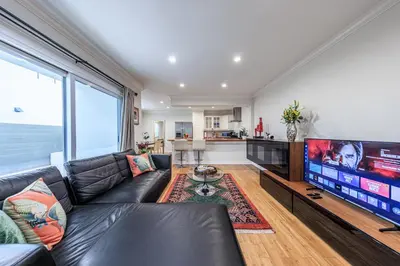 a living room with a black leather couch and a large television at Bright 2 Bedroom Home in the Heart of Santa Monica in Los Angeles