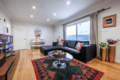 a living room with a black leather couch and a glass table at Bright 2 Bedroom Home in the Heart of Santa Monica in Los Angeles
