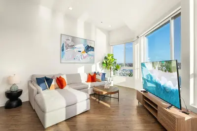 a living room with a white couch and a large tv at Ocean's Edge 2BR Penthouse - Infinite Blue Views in Los Angeles