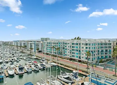 a marina with boats docked in front of a large building at Ocean's Edge 2BR Penthouse - Infinite Blue Views in Los Angeles