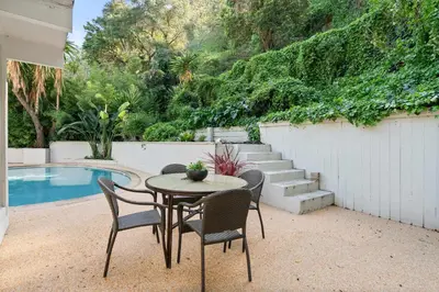 a patio with a table and chairs next to a pool at Beverly Hills Canyon Estate by Colby & Conrad in Los Angeles