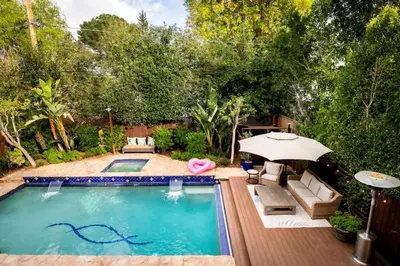 a swimming pool with an umbrella and chairs at Sherman Oaks Home w Pool, Spa and Outdoor Kitchen in Los Angeles