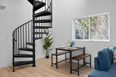 a black spiral staircase in a living room with a table at New Listing Iconic Venice Living by Colby & Conrad in Los Angeles