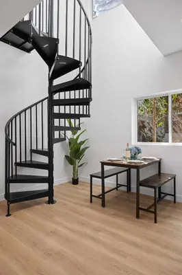 a black spiral staircase in a living room with a table at New Listing Iconic Venice Living by Colby & Conrad in Los Angeles