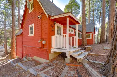 a red tiny house in the middle of the forest at Walk to Lake Arrowhead Village Bright Gem with Deck in Lake Arrowhead