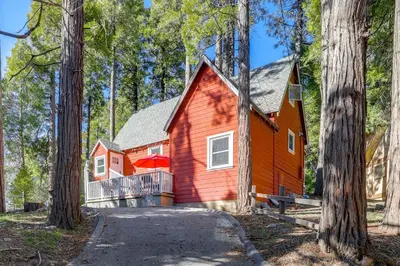 a red house in the middle of a forest at Walk to Lake Arrowhead Village Bright Gem with Deck in Lake Arrowhead