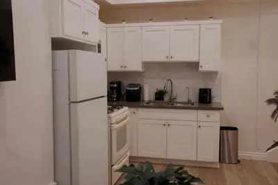 a kitchen with white cabinets and a white refrigerator at The Sunset Gathering in Los Angeles