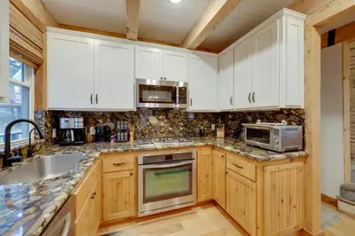 a kitchen with white cabinets and a sink and a microwave at 1 Mi to Lake Arrowhead! All-Season Family Getaway in Lake Arrowhead