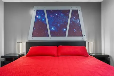 a bedroom with a red bed with a window at Star Wars Retreat by OC Adventure Homes in Garden Grove