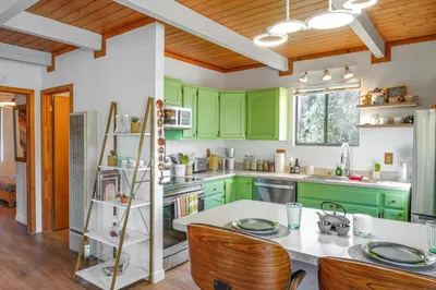 a kitchen with green cabinets and a table and chairs at Mtn Views Near Hiking Pine Mountain Club Getaway! in Pine Mountain Club