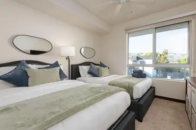 two beds in a room with a window at West Hollywood Chic Apartment in Los Angeles