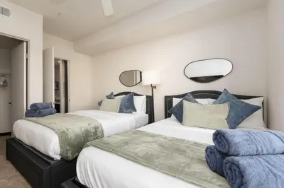 a bedroom with two beds with blue pillows at West Hollywood Chic Apartment in Los Angeles
